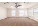 Bright bedroom featuring three large windows, plush carpeting, and a contemporary ceiling fan at 1319 Red Baron Ln, Boulder City, NV 89005