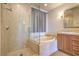 Luxurious bathroom with glass-enclosed shower, separate soaking tub, and marble tile surround at 15 Via Mantova # 302, Henderson, NV 89011