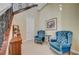 Charming seating area with two blue armchairs, small table, and elegant artwork under the staircase at 16 Mallard Creek Trl, Henderson, NV 89052