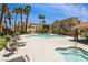 Community pool with plenty of lounge chairs, surrounded by mature palm trees under a bright blue sky at 1836 N Decatur Blvd # 203, Las Vegas, NV 89108