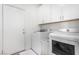 Well-lit laundry room with white washer and dryer, white cabinets, and door to access the space at 288 Whitney Crest St, Henderson, NV 89015