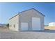 Exterior view of a large outbuilding featuring multiple garage doors and ample parking space at 3580 Prairie Ave, Pahrump, NV 89048