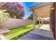 Covered patio and artificial grass in a fenced backyard with lush landscaping at 437 Via Stretto Ave, Henderson, NV 89011