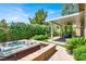 Relaxing backyard with a hot tub, covered patio, barbecue, and lush greenery at 4937 Graziano Ave, Las Vegas, NV 89141