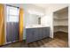 Bathroom with dual vanity and grey cabinets, next to a walk-in closet and window at 6101 Cavalry Trl, Pahrump, NV 89060