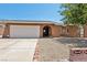 Charming single-story home featuring a two-car garage, an arched entryway, and desert landscaping at 667 Del Prado Dr, Boulder City, NV 89005