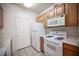 Cozy kitchen featuring wooden cabinetry, white appliances, and tile flooring at 7155 S Durango Dr # 205, Las Vegas, NV 89113