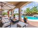 Inviting covered patio with a fire pit and views of the pool and lush landscaping at 7794 River Mist Ct, Las Vegas, NV 89113