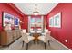 Bright dining room with a round glass table, modern light fixture, and vibrant red walls at 7794 River Mist Ct, Las Vegas, NV 89113