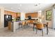 Modern kitchen with stainless steel appliances, wooden cabinets, an island with bar seating, and adjacent dining area at 7794 River Mist Ct, Las Vegas, NV 89113