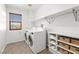 Well-organized laundry room with washer, dryer, built-in shelving, and a window for natural light at 7794 River Mist Ct, Las Vegas, NV 89113