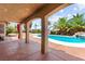 Covered patio with decorative pillars overlooks the in-ground pool and tropical landscaping at 7794 River Mist Ct, Las Vegas, NV 89113