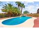 A serene in-ground pool features mature palm trees and a rock waterfall feature at 7794 River Mist Ct, Las Vegas, NV 89113