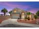 Inviting two-story home featuring desert landscaping, a two-car garage, and warm exterior lighting at 9011 Aldershot Ct, Las Vegas, NV 89147