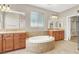 This primary bathroom features dual vanities and a soaking tub with tile surround at 9225 Dalmahoy Pl, Las Vegas, NV 89145