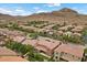 An aerial view of a neighborhood with red tile roofs in front of a mountain range under a blue sky with white clouds at 10300 S Dapple Gray Rd, Las Vegas, NV 89178