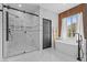 Modern bathroom featuring a sleek glass-enclosed shower and elegant soaking tub near a bright window at 10300 S Dapple Gray Rd, Las Vegas, NV 89178