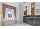 Modern bathroom with dual vanity, soaking tub, wood accent wall, and marble tile at 10300 S Dapple Gray Rd, Las Vegas, NV 89178