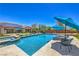 Relaxing backyard with a sparkling pool, spa, lounge chairs, patio seating, and solar panels on the roof at 10319 Larkmead Ave, Las Vegas, NV 89149