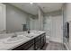 Modern bathroom featuring double sinks, a dark vanity, and glass enclosed shower at 10360 Pescado Ln, Las Vegas, NV 89135