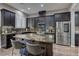 Modern kitchen features dark cabinetry, stainless steel appliances, granite countertops, and an island with bar seating at 10360 Pescado Ln, Las Vegas, NV 89135