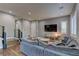 Open-concept living room with hardwood floors, a large sectional sofa, and staircase leading to the second floor at 10360 Pescado Ln, Las Vegas, NV 89135