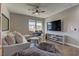 Living room with a large sofa, media center, television and stylish ceiling fan at 10360 Pescado Ln, Las Vegas, NV 89135
