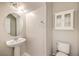 Bathroom with white pedestal sink, matching white toilet and cabinet and round mirror at 1064 Calvia St, Las Vegas, NV 89138