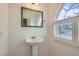 Stylish bathroom featuring a pedestal sink, decorative mirror, and shuttered window at 1547 Balsam Mist Ave, Las Vegas, NV 89183