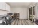 Bright laundry room with gray-toned plank flooring, gray washer and dryer, and sliding glass doors at 1832 Merze Ave, Henderson, NV 89011