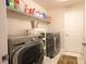 Laundry room featuring modern washer and dryer, tile floor, and functional shelving at 2913 Monate Ct, Henderson, NV 89044