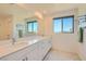 Bright bathroom featuring a dual sink vanity, a large mirror, and a window letting in natural light at 3194 Lumassina Way, Henderson, NV 89044