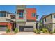 A modern home with a gray stucco and red siding exterior, and well-manicured landscaping at 3194 Lumassina Way, Henderson, NV 89044