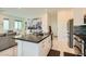 Modern kitchen featuring an island with a dark countertop, white cabinets, and stainless steel appliances at 3194 Lumassina Way, Henderson, NV 89044