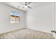 Bright bedroom with neutral carpet, white walls, a ceiling fan, and a window overlooking the exterior at 348 Andy Wheeler Dr, Henderson, NV 89011
