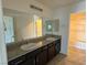 Bathroom featuring double sink vanity with granite counters, framed mirror and tiled floors at 4104 Free Bird Crest Ave, North Las Vegas, NV 89081