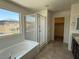 Bright bathroom featuring a soaking tub, glass shower, and a large window with neighborhood views at 4104 Free Bird Crest Ave, North Las Vegas, NV 89081