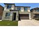 Two story home featuring a two car garage, paved driveway, and minimal maintenance artificial grass at 4104 Free Bird Crest Ave, North Las Vegas, NV 89081