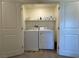 A bright laundry room is shown with a washer, a dryer, and shelving for supplies, all behind folding closet doors at 4273 Venus Falls Ave, North Las Vegas, NV 89084
