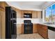 Functional kitchen features wood cabinets, modern black appliances, and a bright window at 5155 W Tropicana Ave # 2017, Las Vegas, NV 89103
