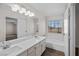 Well-lit bathroom features double sinks, a long mirror, and a tub under a window with security bars at 5458 Walton Heath Ave, Las Vegas, NV 89142