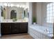 Bathroom featuring a double vanity, mirrors, a soaking tub, and hardwood floors at 904 Swift Bear St, Henderson, NV 89002