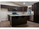 Modern kitchen featuring dark cabinets, stainless steel appliances, and a center island with granite countertops at 904 Swift Bear St, Henderson, NV 89002