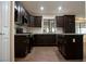 Well-equipped kitchen featuring dark cabinetry, stainless steel appliances, an island, and tile backsplash at 904 Swift Bear St, Henderson, NV 89002
