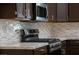 Close-up of the kitchen featuring stainless steel gas range, microwave, tile backsplash, and granite countertops at 904 Swift Bear St, Henderson, NV 89002