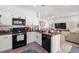 Modern kitchen with white cabinets, a black dishwasher, and an adjacent living area at 9105 Chenin Ave, Las Vegas, NV 89129