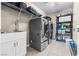 Well-equipped laundry room with sleek, modern washer and dryer units, shelving and a utility sink at 9163 W Torino Ave, Las Vegas, NV 89148