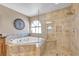 A well-lit bathroom with a glass-enclosed shower, a tub beneath a window, and vanity with storage at 9435 Westwind Rd, Las Vegas, NV 89139