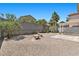 Spacious backyard with gravel, privacy fence, landscaping, benches, and covered patio area at 9625 Gatesville Ave, Las Vegas, NV 89148