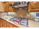 Close-up of kitchen with granite countertop, stainless steel gas cooktop, and wooden cabinetry at 9733 Plateau Heights Pl, Las Vegas, NV 89144
